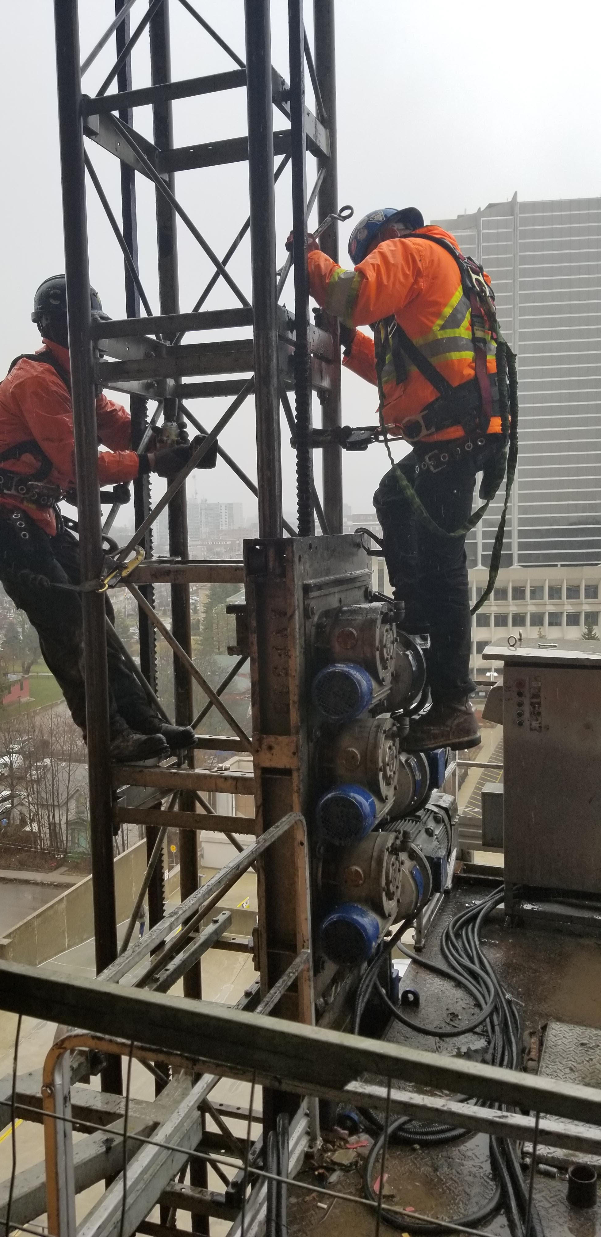 Certified mechanics maintaining a hoist.